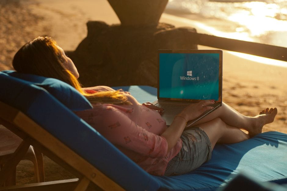 Digital nomad working on a laptop at a beachside cafe with a passport nearby